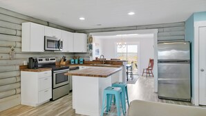 Une cuisine moderne avec des meubles blancs, un réfrigérateur en acier inoxydable et un îlot central en bois doté de tabourets.