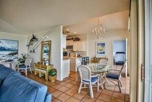 Un salón amplio con una mesa de comedor, sillas, un sofá y una cocina al fondo.