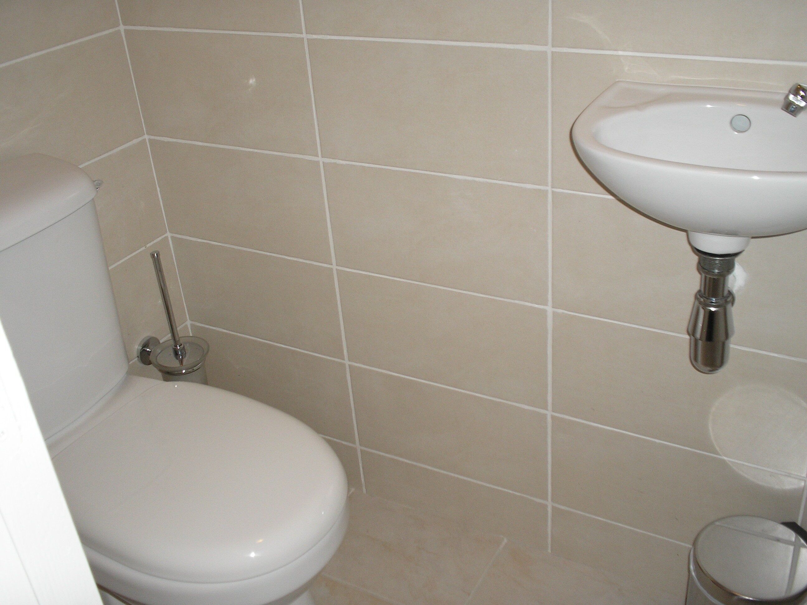 Un baño con inodoro, lavamanos y un pequeño cubo de basura.