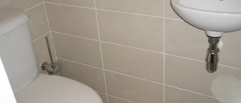 Un baño con inodoro, lavamanos y un pequeño cubo de basura.
