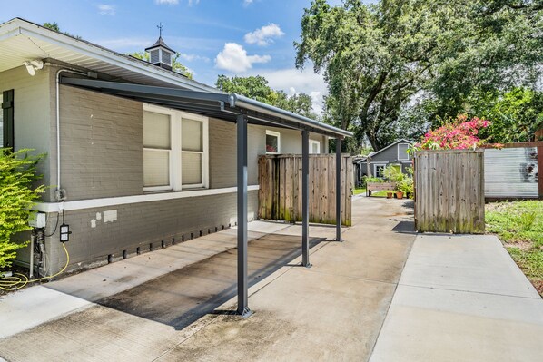 A residential building with a garage, a covered outdoor area, and a wooden fence.