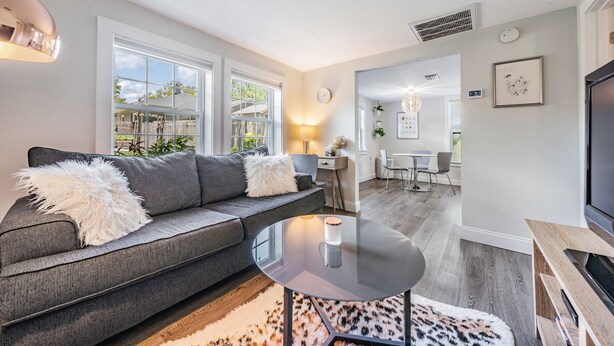 Un salon moderne avec un canapé gris, une table basse en verre et un tapis à motifs léopard.