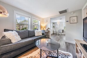 A modern living room with a grey sofa, a glass coffee table, and a leopard print rug.