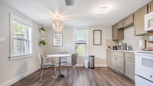 Une cuisine moderne avec un coin repas, comprenant une table ronde, des chaises et un lustre.