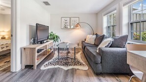 Un salon moderne avec un canapé gris, un téléviseur à écran plat, une table basse et un tapis à motifs léopard.