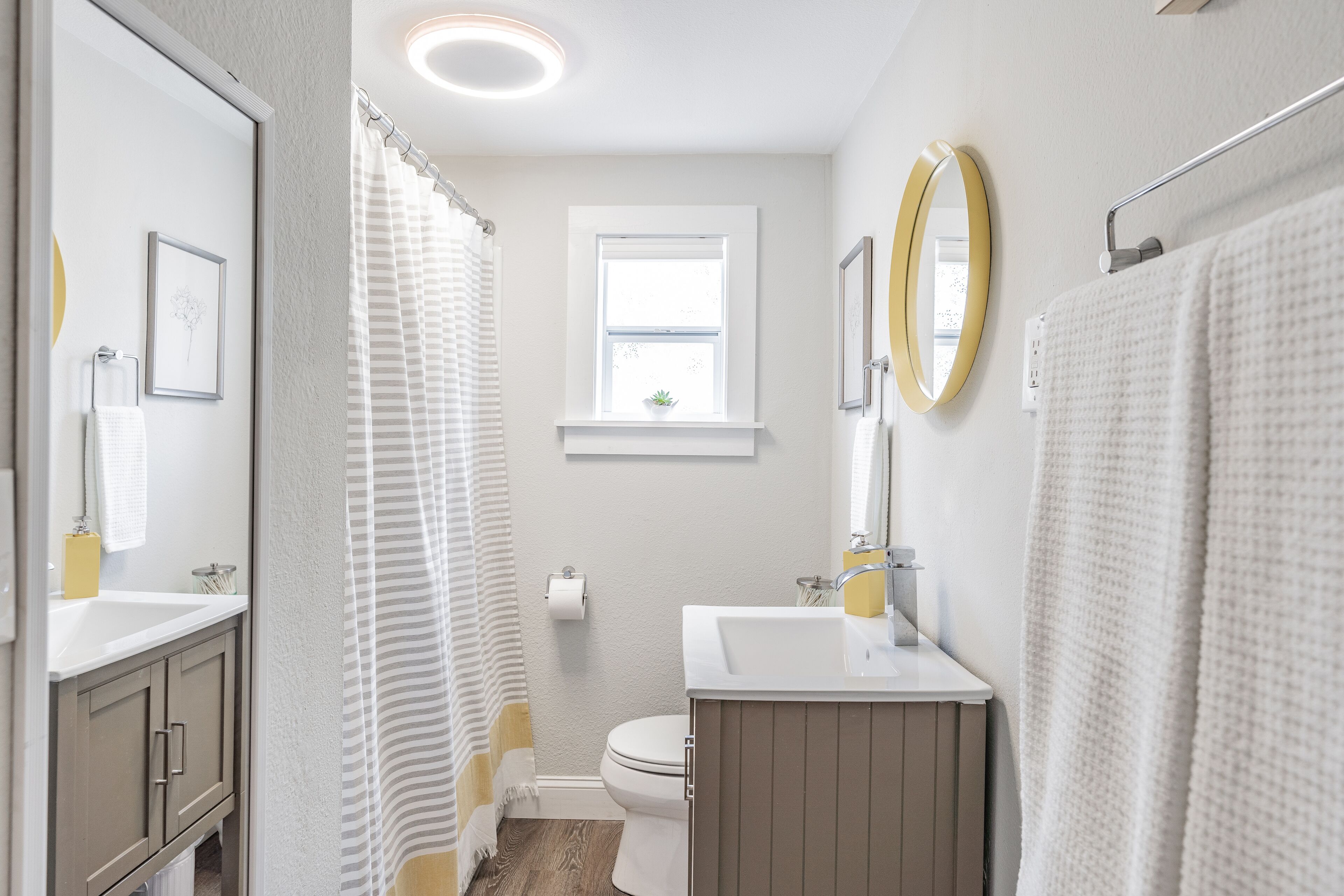 A bathroom with a toilet, a sink, a mirror, and a shower curtain.