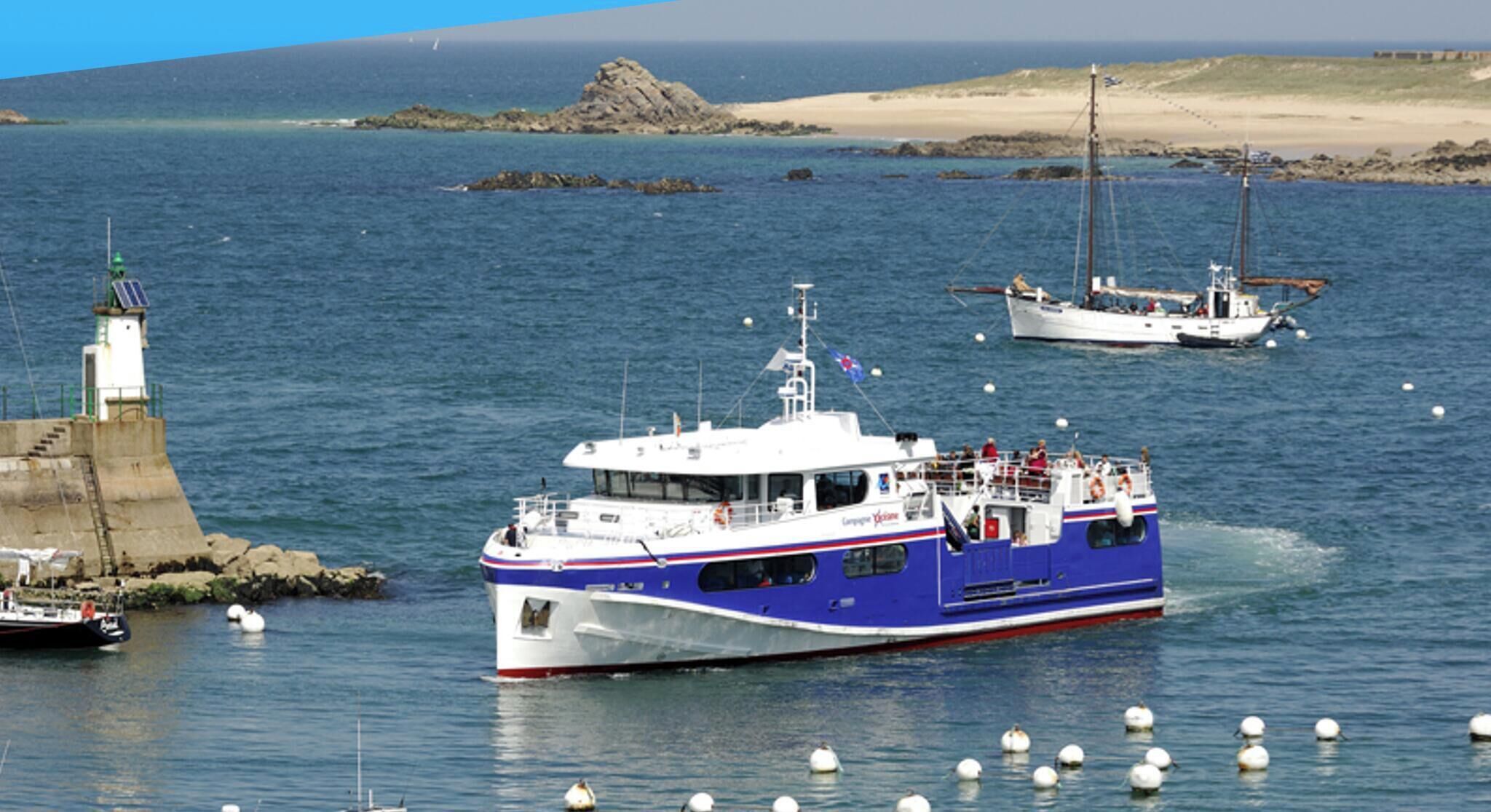 Un paysage côtier avec un bateau bleu et blanc amarré près d’un phare et de formations rocheuses.