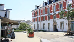 Um hotel com fachada vermelha e branca, várias janelas e entrada visível.