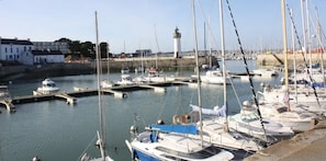 Un puerto deportivo con barcos amarrados, un faro y edificios al fondo.