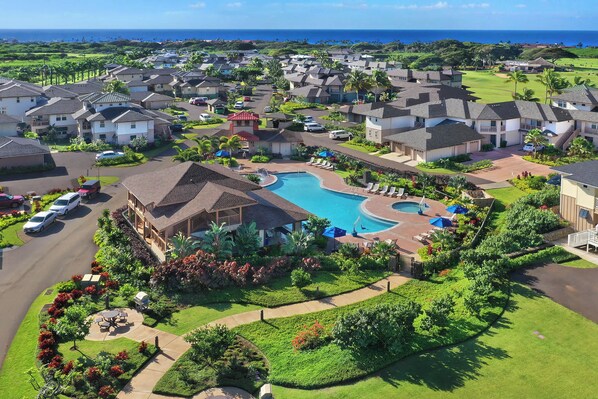 Zona residencial con piscina, rodeada de casas, un campo de golf y vistas despejadas al océano.