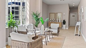 Una moderna hall d'albergo con area salotto, ampie finestre e una reception.