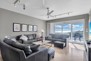 A modern living room with leather sofas, a coffee table, and a view of the ocean through large sliding glass doors.