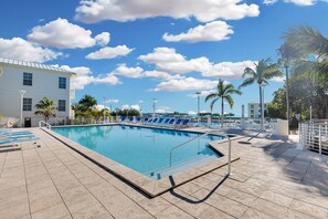 A swimming pool with blue chairs, a lifebuoy, and a clear sky.