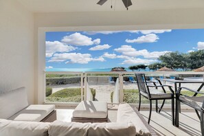 A balcony with a view of the beach, lounge chairs, and a table. - Mariners Club # 314  3 Bed 2.5 Bath Key Largo Beachfront Luxury Ocean views and 3 bedroom 2.5 bath condo (Key Largo)