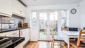 A modern kitchen with white cabinets, a black countertop, and a dining area with wooden chairs and a table.