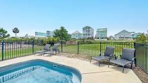 A swimming pool with lounge chairs, a fenced area, and buildings in the background. - DOG FRIENDLY! EAST SIDE OF DUPLEX, PRIVATE BALCONY - BEACHBALL PROPERTIES (Gulf Shores)