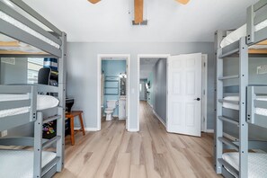 A room with bunk beds, a wooden floor, and a door leading to another room. - DOG FRIENDLY! EAST SIDE OF DUPLEX, PRIVATE BALCONY - BEACHBALL PROPERTIES (Gulf Shores)