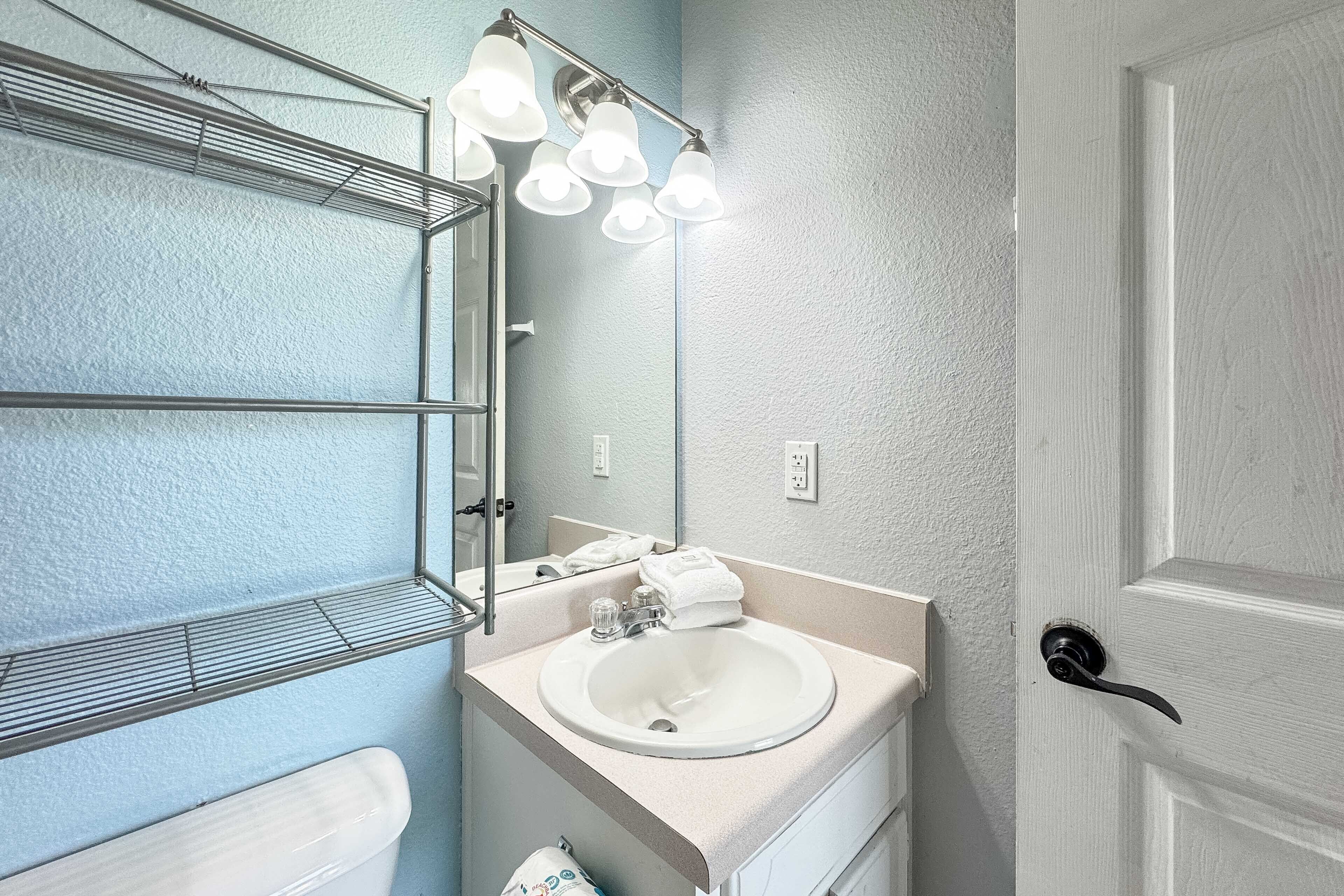 A bathroom with a white sink, a mirror, and a towel rack.