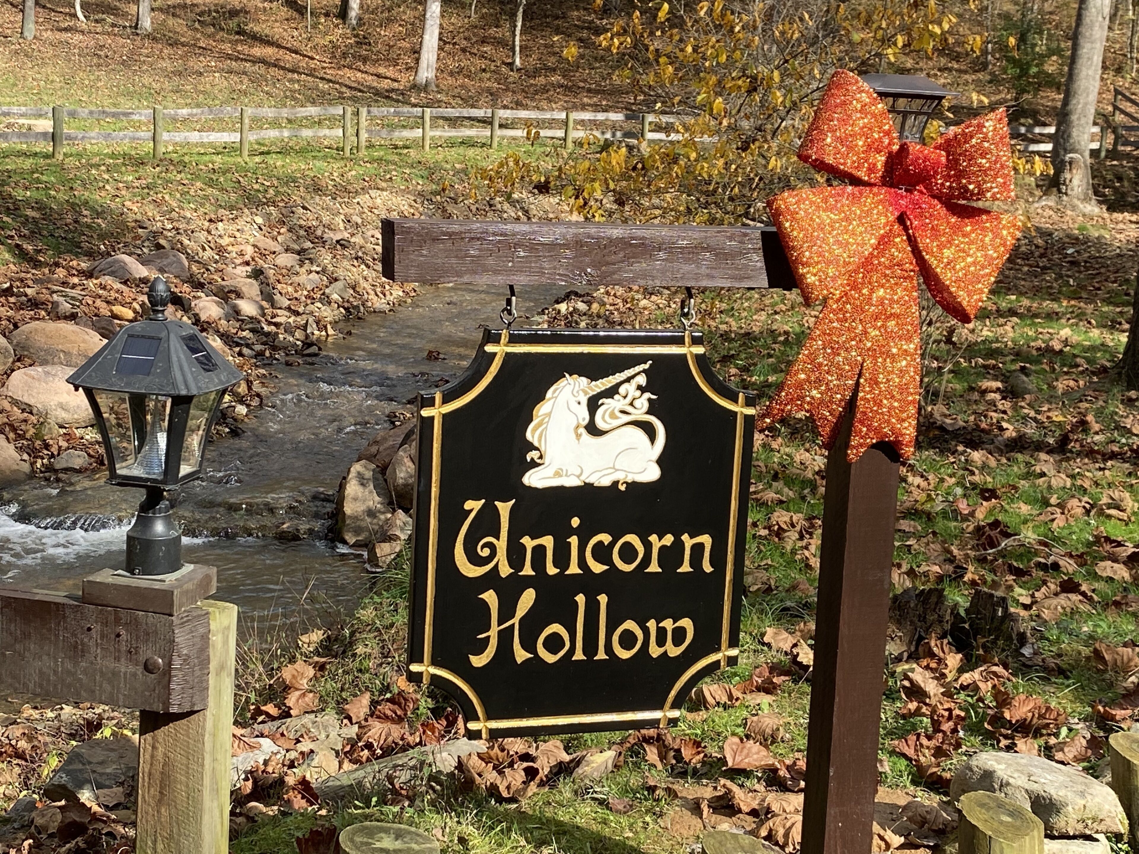 En skylt för Unicorn Hollow med en illustration av en enhörning och en pilbåge.