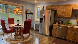 Una cocina moderna con armarios de madera, electrodomésticos de acero inoxidable y un comedor con sillas rojas y una mesa de vidrio.