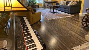 Una sala de estar con un piano, un sofá, una mesa de centro y una lámpara.