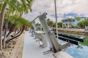 A waterfront property with a pool, palm trees, and a building with a light blue facade.