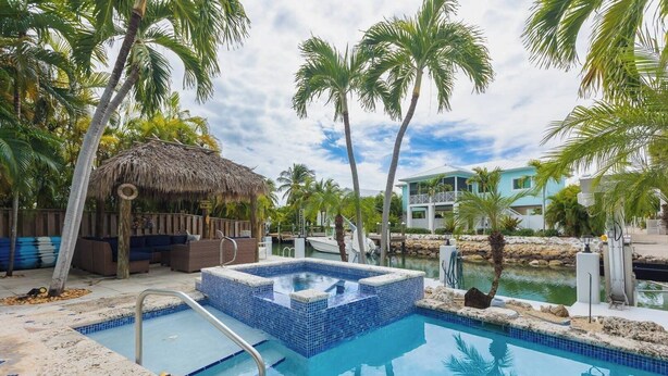 Piscina con jacuzzi, zona de descanso y vista al agua y edificios.
