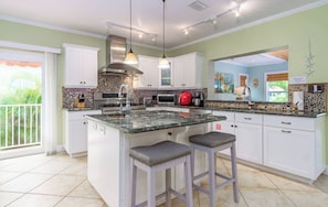 A modern kitchen with a central island, white cabinetry, and a large window.