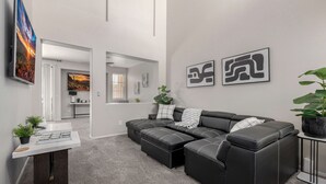 Ein modernes Wohnzimmer mit einer Eckcouch, einem Couchtisch und Kunstwerken an den Wänden.