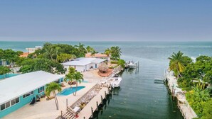 A waterfront property with a swimming pool, docked boat, and lush greenery. - Yellowtail for Dinner – Ground-Level Waterfront 3BR Home with Pool & Dock on the Gulfside (Marathon)