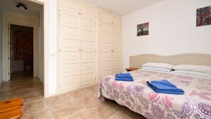 Een slaapkamer met een bed, een kledingkast en een deur naar een andere kamer.
