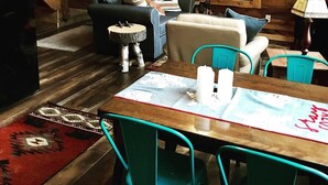 A cozy cabin interior with a wooden interior, a green door, a sofa, a dining table with chairs, and a staircase. - Balsam Hollow Cabin in the Adirondacks (Bloomingdale)