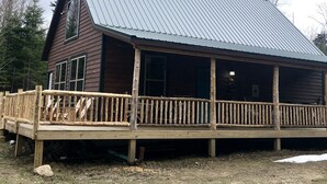 A wooden cabin with a metal roof, a wooden deck, and a large window. - Balsam Hollow Cabin in the Adirondacks (Bloomingdale)