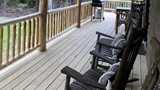 A wooden deck with a covered area, wooden railings, and a grill cart. - Balsam Hollow Cabin in the Adirondacks (Bloomingdale)