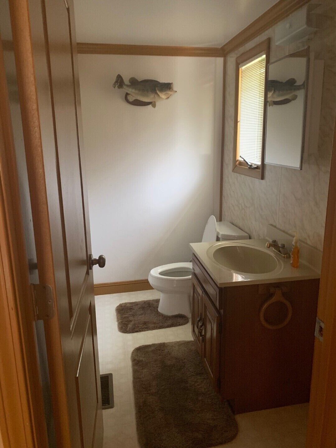 A bathroom with a toilet, sink, and a decorative fish on the wall.