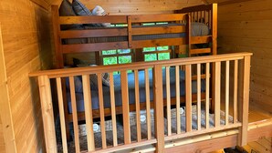 A wooden cabin with a loft bed and a lower bunk bed, both with storage compartments. - Emerald Forest Treehouse - From Treehouse Masters (Redmond)