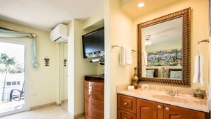 A bathroom with a large mirror, wooden vanity, and a television mounted on the wall. - Comfy Condo 1bed/1bath nightly condo with pool (Marathon)
