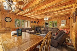 Ein Holzinterieur mit einem Esstisch, Sofas und einem Deckenventilator.
