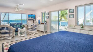 A bedroom with a large bed, a television, a desk, and a view of the ocean. - Palm Point 3bed/2bath single family home with open water views, private pool & dockage (Marathon)