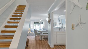 Un interior moderno con una escalera de madera, una zona de comedor y una cocina.