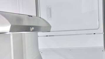 Uma lavanderia com máquina de lavar e secadora Whirlpool empilhadas.