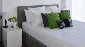 A bedroom with a bed, nightstand, and wall art. - Cozy Stays Cayala Apartments 2 (Zone 16)