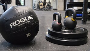 A gym with exercise equipment including a Rogue medicine ball, kettlebells, and weight plates. - Cozy Stays Cayala Apartments 2 (Zone 16)