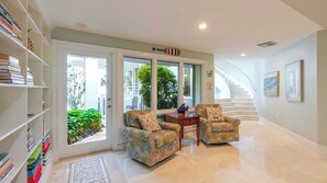 A spacious living area with a sofa set, a bookshelf, and a staircase.