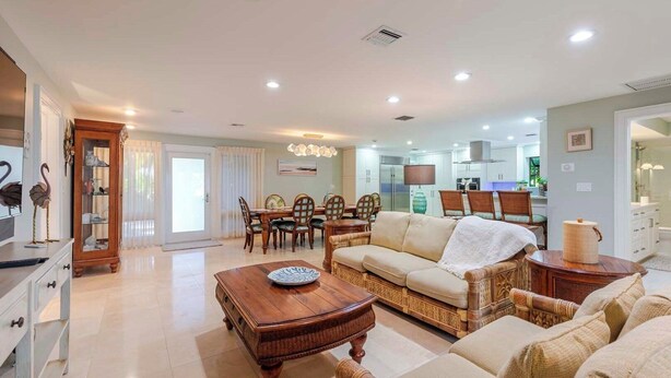 A spacious living room with a sofa, coffee table, and dining area with chairs. - Shangri-La 3 Bedroom 3 Baths Gulf Front Estate (Marathon)