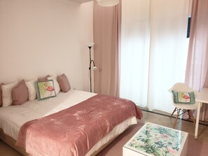 A bedroom with a bed, a bedside table, a chair, and a window with curtains.