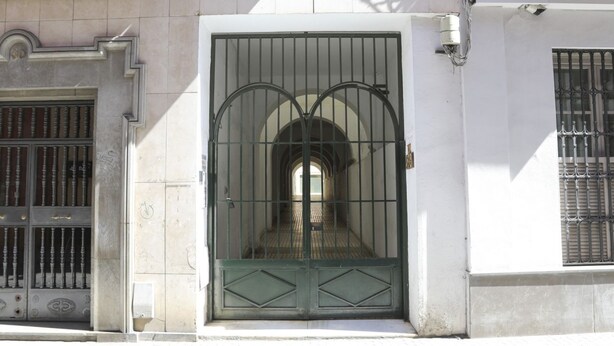 Un bâtiment blanc avec une grande porte en métal et une fenêtre grillagée.