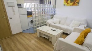 Une petite pièce propre, avec un canapé blanc, une petite table et un lave-linge.