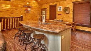 A wooden interior with a bar area featuring stools, a sink, and a 'welcome' sign. - Splashin' Around! 3 Bedroom with a Pool! Minutes from downtown Pigeon Forge. (Sevierville)