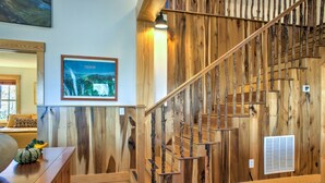 Eine Holztreppe mit rustikalem Design, ein gerahmtes Bild an der Wand und eine Holzbank mit Kürbissen.